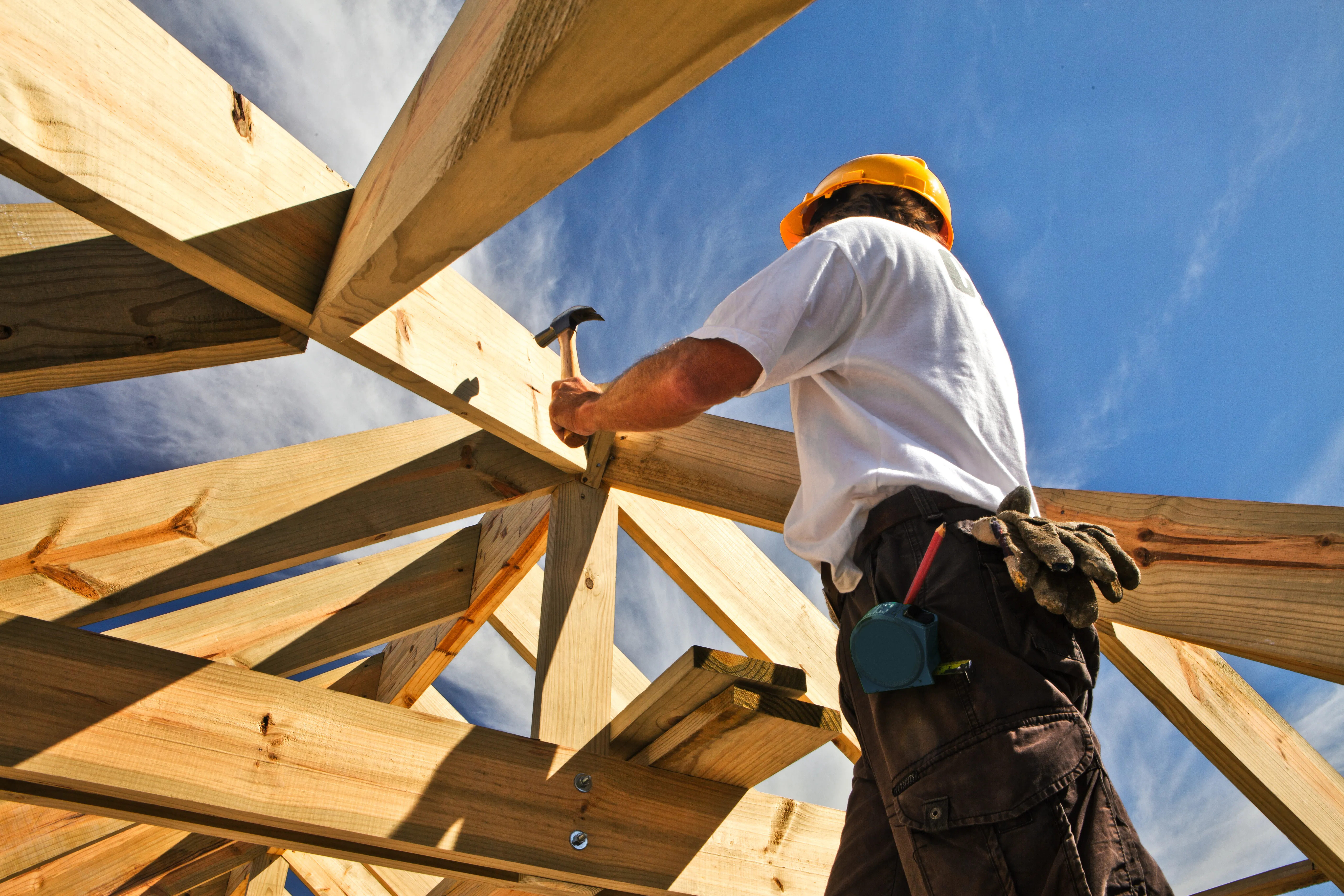 Professional carpenter working on a wooden roof structure under a clear blue sky in Los Angeles, representing Best Construction LA services.
