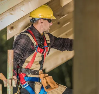 Professional general contractor working at a residential construction site in Los Angeles with safety harness equipment.